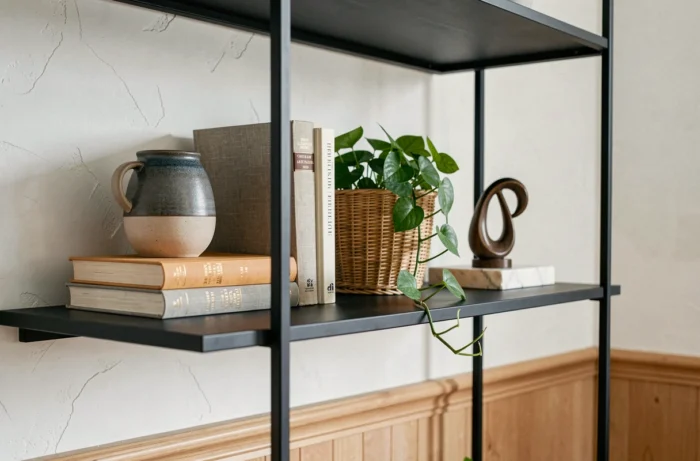 Étagère décorée avec céramiques artisanales, livres d'art et plante verte selon les tendances déco actuelles